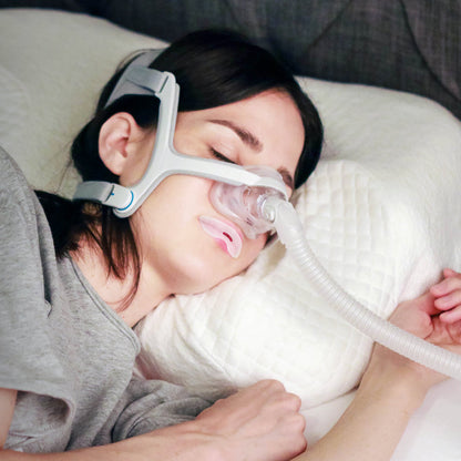 Woman lying in bed using a CPAP machine with mouth tape